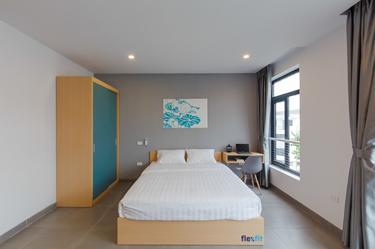 Không gian phòng ngủ pha phối các màu sắc vô cùng tinh tế tạo nên sự dễ chịu cho bất cứ ai bước vào căn phòng này. Giường ngủ gỗ vân sáng sử dụng bộ chăn ga gối đệm tông trắng hòa hợp với các mảng xanh của tủ, của tranh treo tường.
