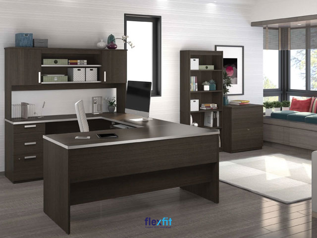 Bàn làm việc chữ U màu nâu gỗ trầm phối viền trắng tạo điểm nhấn cho không gian. Ngoài ngăn kéo tủ dưới bàn, trên bàn còn tích hợp giá để đồ, trang trí làm tăng tính thẩm mỹ của phòng làm việc.